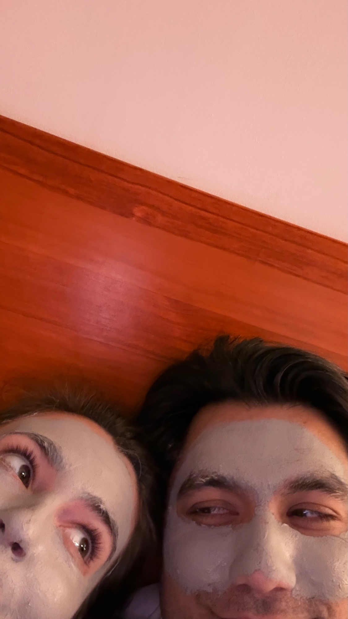 Kyle and Elise lying down in face masks, being goofy