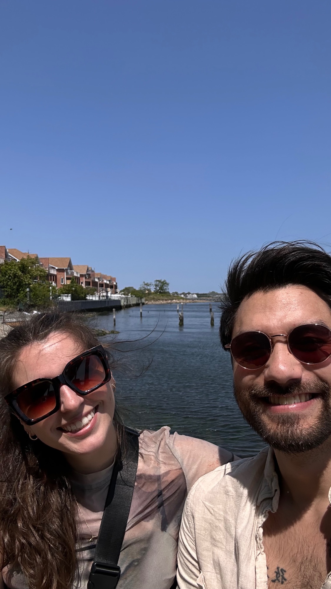 Kyle and Elise in sunglasses on a sunny waterfront